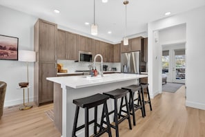 A modern kitchen with wooden cabinets, a white island with bar stools, stainless steel appliances, and pendant lighting. - 106 Homestead Loop Luxury 3 bedroom, mt view, private patio, outdoor HT (Fraser)