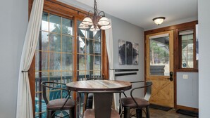 A dining area with a round table and four chairs, a wooden door, and a window with curtains. - Kicking Horse Buckskin 3-205 Family friendly 2 bed private deck & mountain views (Granby)