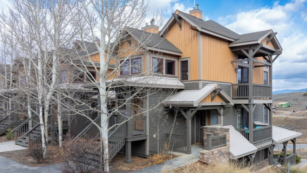 A two-story house with a wooden exterior, a balcony, and a staircase leading to the upper level. - Kicking Horse Buckskin 3-205 Family friendly 2 bed private deck & mountain views (Granby)
