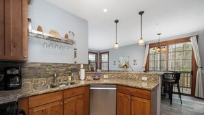 A kitchen with granite countertops, wooden cabinets, a dishwasher, and a coffee maker. - Kicking Horse Buckskin 3-205 Family friendly 2 bed private deck & mountain views (Granby)