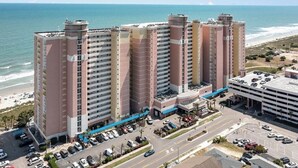 Un hotel moderno de muchas plantas, con estacionamiento y vista al mar.