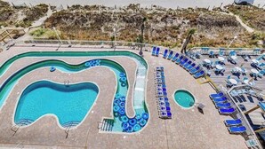 Una piscina de forma singular, rodeada de sillones de descanso y una piscina pequeña para niños.