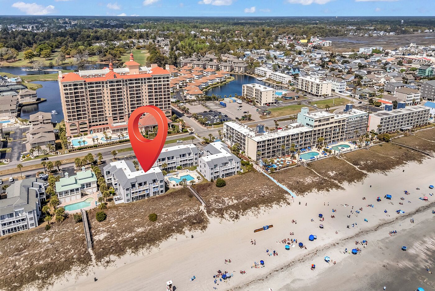 Zona hotelera frente al mar con varios edificios, una playa y un puerto deportivo.