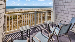 A balcony with a view of the beach, a table, and two chairs. - Newly Renovated Oceanfront 3BR at Sea Cloister ll | Cherry Grove (North Myrtle Beach)