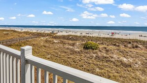 A beach with a wooden deck in the foreground. - Newly Renovated Oceanfront 3BR at Sea Cloister ll | Cherry Grove (North Myrtle Beach)