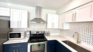 A modern kitchen with stainless steel appliances, white cabinets, and a hexagonal tile backsplash.