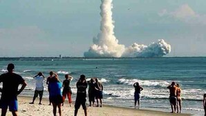 A beach with people and a large plume of smoke or fire in the distance. - Stunning 1 brm: beach across street, port 8 mi, Ron Jon 4 mi, nightlife 1.6 mi (Cocoa Beach)
