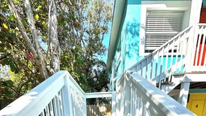 A wooden staircase with white railings leading to a building with a blue exterior and a yellow door. - Stunning 1 brm: beach across street, port 8 mi, Ron Jon 4 mi, nightlife 1.6 mi (Cocoa Beach)