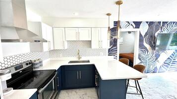 Una cocina moderna con una isla central, electrodomésticos integrados y un salpicadero con diseño.
