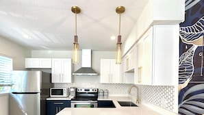 A modern kitchen with a central island, stainless steel appliances, and pendant lighting. - Stunning 1 brm: beach across street, port 8 mi, Ron Jon 4 mi, nightlife 1.6 mi (Cocoa Beach)