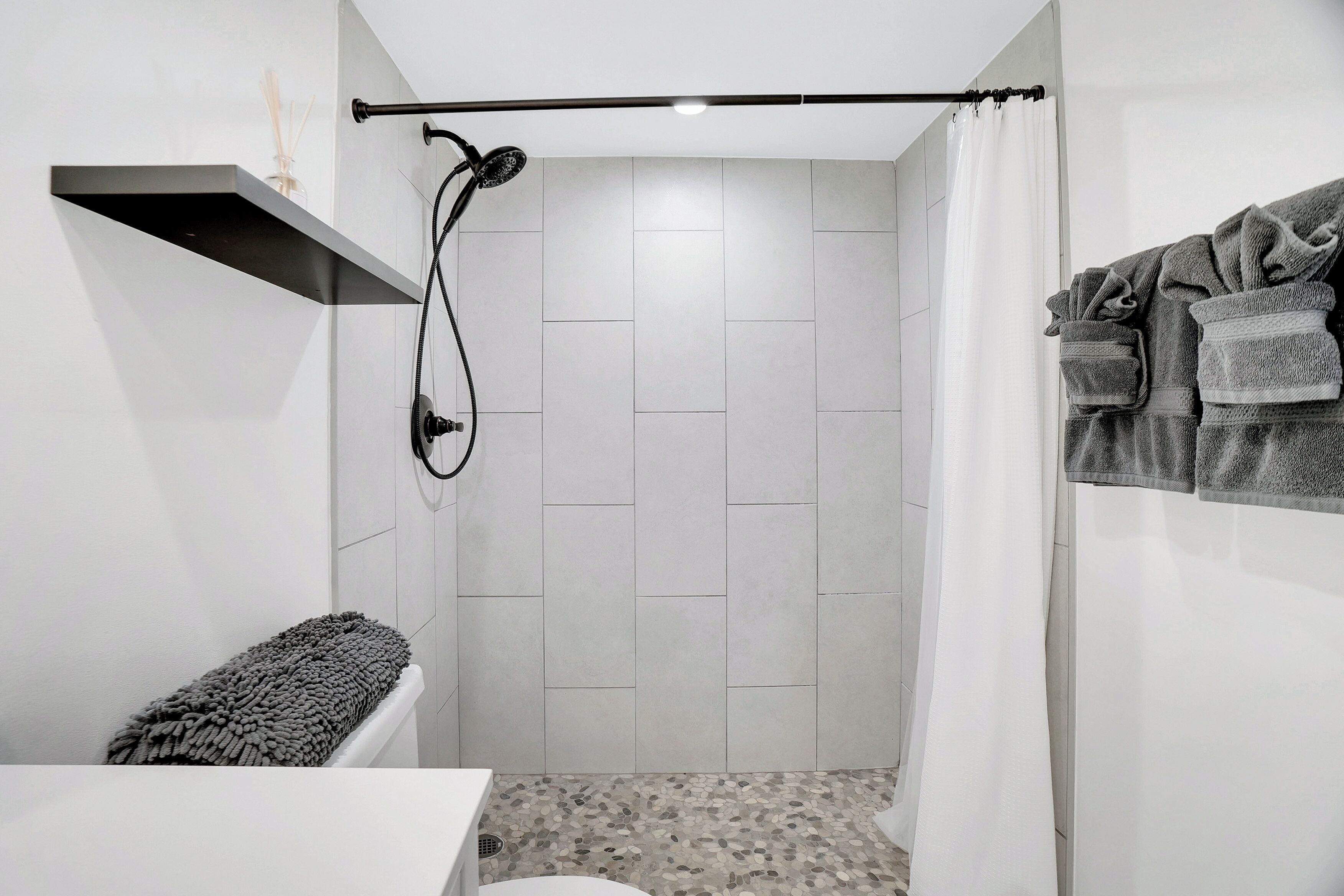 Un baño moderno con ducha, inodoro y barra para toallas.