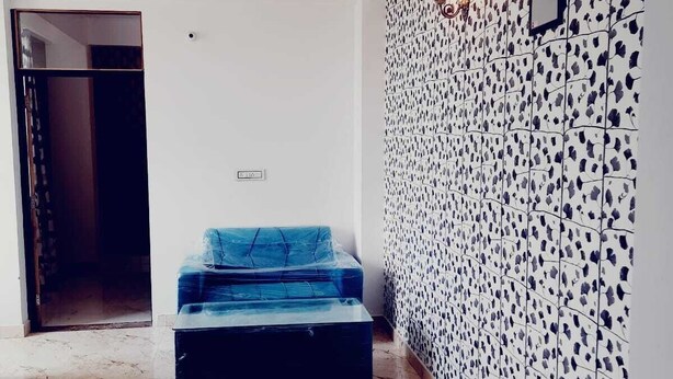 A room with a marble floor, a blue sofa, a patterned wall, and a ceiling fan. - Elegant 3-bedroom apartment in Rajawas (Rajawas)