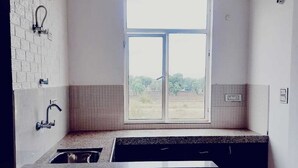 A modern kitchen with a large window, a built-in sink, and a pendant light. - Elegant 3-bedroom apartment in Rajawas (Rajawas)