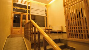 Una escalera con barandillas y pasamanos de madera que conduce a una habitación con un ventanal grande y una puerta de madera.
