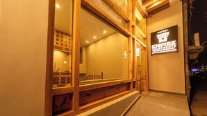 Entrada de un hotel con amplios ventanales, una escalera de madera y un letrero que dice "EMPIRE APARTMENTS".