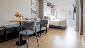 Ein modernes Wohnzimmer mit Sofa, Esstisch und Bett.