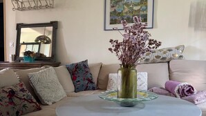 A living room with a round coffee table, a floral vase, and a patterned rug. - Vacqueyras: Mas L'Epicure - bright apartment with shared pool and garden (Vacqueyras)