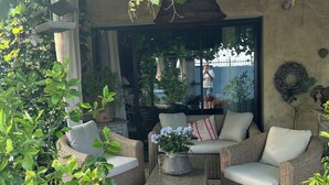 A cozy outdoor seating area with wicker furniture, a patterned rug, and a potted plant. - Vacqueyras: Mas L'Epicure - bright apartment with shared pool and garden (Vacqueyras)