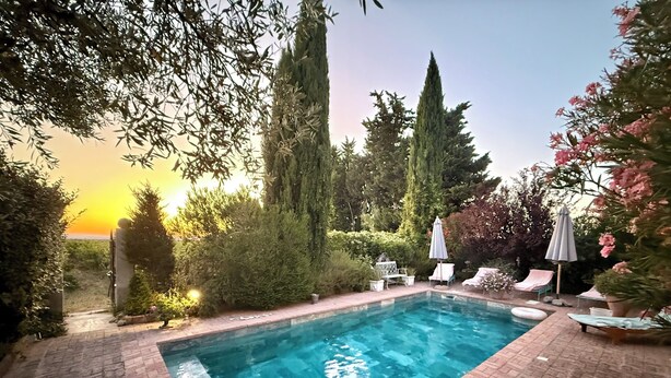 A rectangular swimming pool with a brick border, surrounded by lush greenery and tall trees. - Vacqueyras: Mas L'Epicure - bright apartment with shared pool and garden (Vacqueyras)