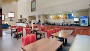 Ein geräumiger Hotel-Speisesaal mit mehreren Tischen und roten Sitzmöglichkeiten.