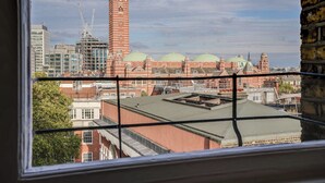 A view of a cityscape with a prominent red brick building with domed roofs, a tall tower, and modern buildings in the background. - Buckingham Palace 4BR Family Stay Cathedral View (London)