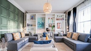 A modern living room with grey sofas, a coffee table, and a bookshelf. - Buckingham Palace 4BR Family Stay Cathedral View (London)