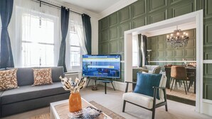 A living room with a sofa, coffee table, and a TV displaying a webpage. - Buckingham Palace 4BR Family Stay Cathedral View (London)
