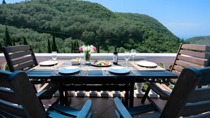 Une table dressée à l’extérieur, avec vue sur une colline boisée.