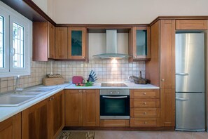 Eine Küche mit Holzausstattung, einem Edelstahlkühlschrank, einem Einbauofen und einem Fenster.