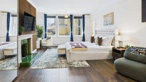 Une chambre moderne avec un grand lit, un canapé, une télévision et une cheminée.