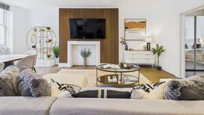 Un salon moderne avec une cheminée, une table basse ronde et un canapé agrémenté de coussins à motifs.