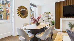 Un espace repas moderne avec une table ronde, des chaises à revêtement gris et un miroir décoratif au mur.