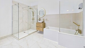 Une salle de bain moderne dotée d’une douche à parois de verre, d’une baignoire sur pieds et d’un meuble-lavabo avec un miroir.