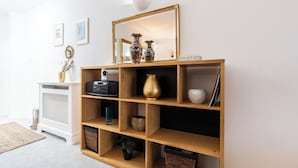 Ein Bücherregal aus Holz mit verschiedenen Dekorationselementen, ein weißer Heizkörper und ein kleiner Tisch mit einer Vase und einer Lampe.