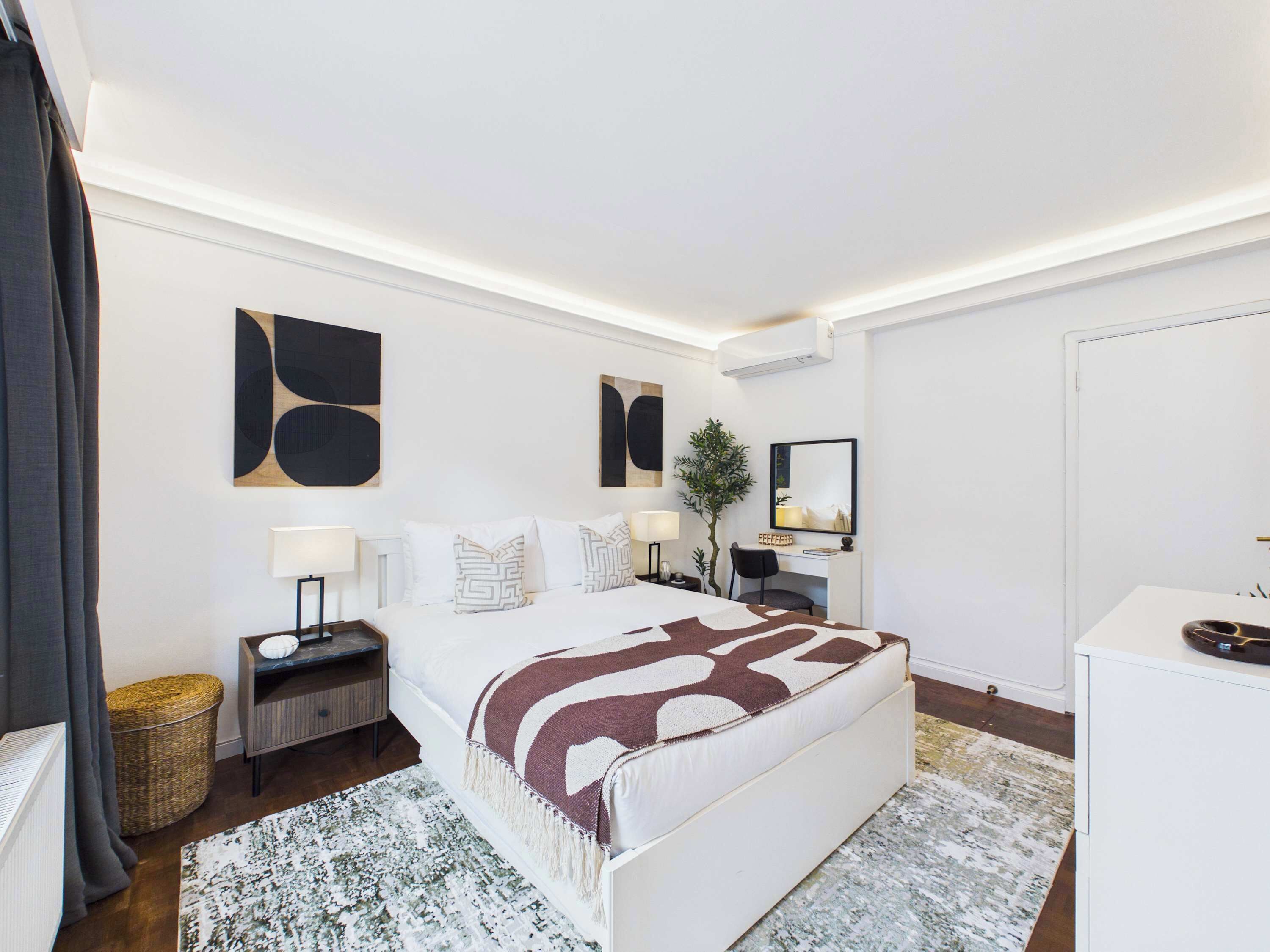 Een moderne hotelkamer met een groot bed, nachtkastjes, een bureau en een spiegel.