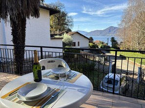 Ein Tisch für zwei, gedeckt mit Wein und einem Glas, mit Blick auf eine malerische Berg- und Wasserausicht.