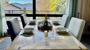 A dining table set for four with a bottle of champagne, glasses, and plates. - Carmen apartment with lake view and balcony (Luino)