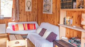 Ein gemütliches Holzhaus-Interieur mit einer Couch, einem Holzesstisch und Regalen mit Büchern und Dekoration.