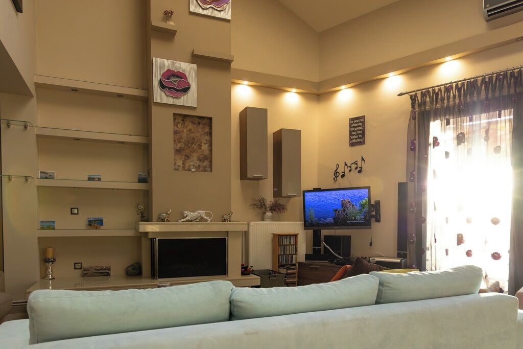 A living room with a sofa, television, fireplace, and decorative items.