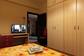 Bedroom with Ample Storage and TV
Functional bedroom featuring a large wardrobe, warm tones, and a TV for added convenience and entertainment.