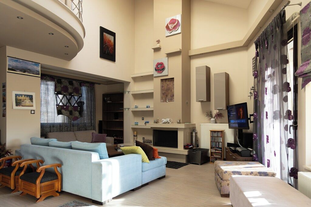 Een ruime woonkamer met een bank, stoelen, een open haard en een televisie.