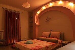 Ein Schlafzimmer mit Bett, Nachttisch, Lampe und einer Wandablage.