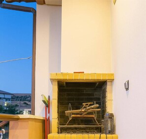 A small outdoor grill area with a chimney, a metal rack, and a metal container.