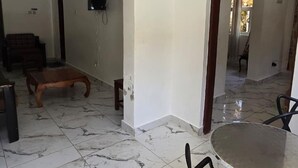 A spacious room with a marble floor, a round table, and a sofa. - Manyatta Azure Boutique Hotel (Diani Beach)