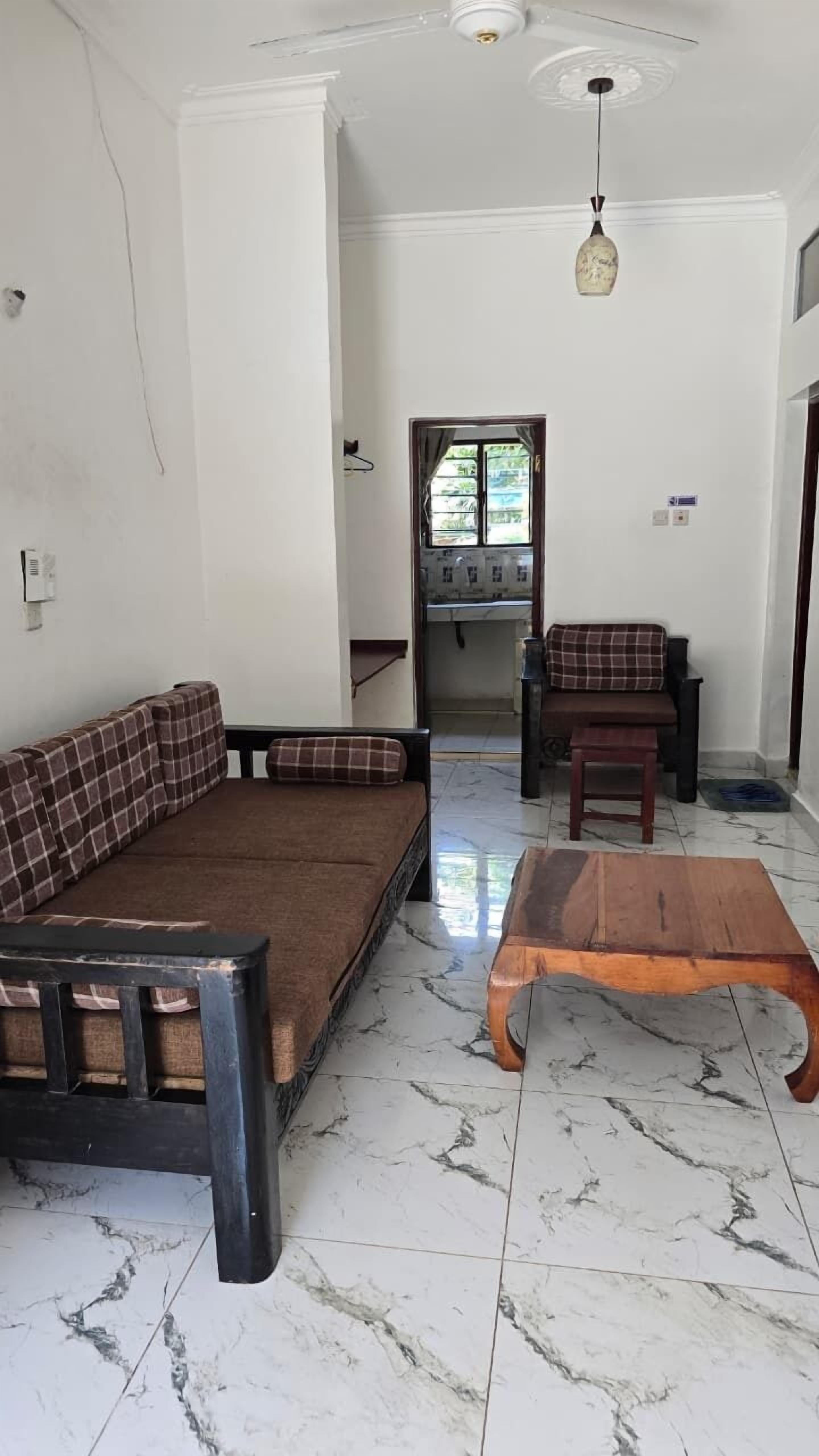 A room with a sofa, a wooden coffee table, and a small table with a chair.
