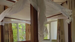 A four-poster bed with a canopy, wooden headboard, and a white and orange bedspread. - Manyatta Azure Boutique Hotel (Diani Beach)