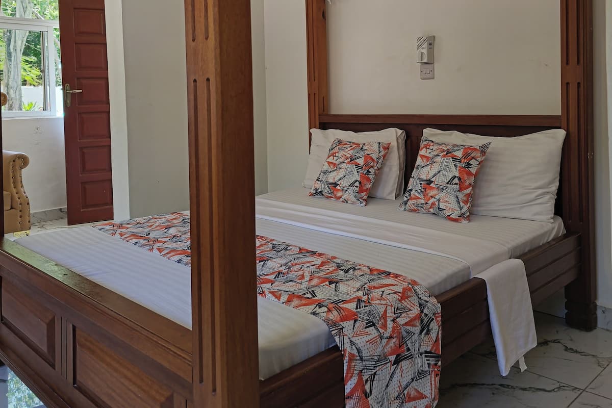 A four-poster canopy bed with a wooden frame and white bedding.