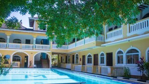 A courtyard with a swimming pool, multiple balconies, and a covered walkway. - Manyatta Azure Boutique Hotel (Diani Beach)