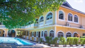 A two-story building with a swimming pool, arched windows, and a balcony. - Manyatta Azure Boutique Hotel (Diani Beach)