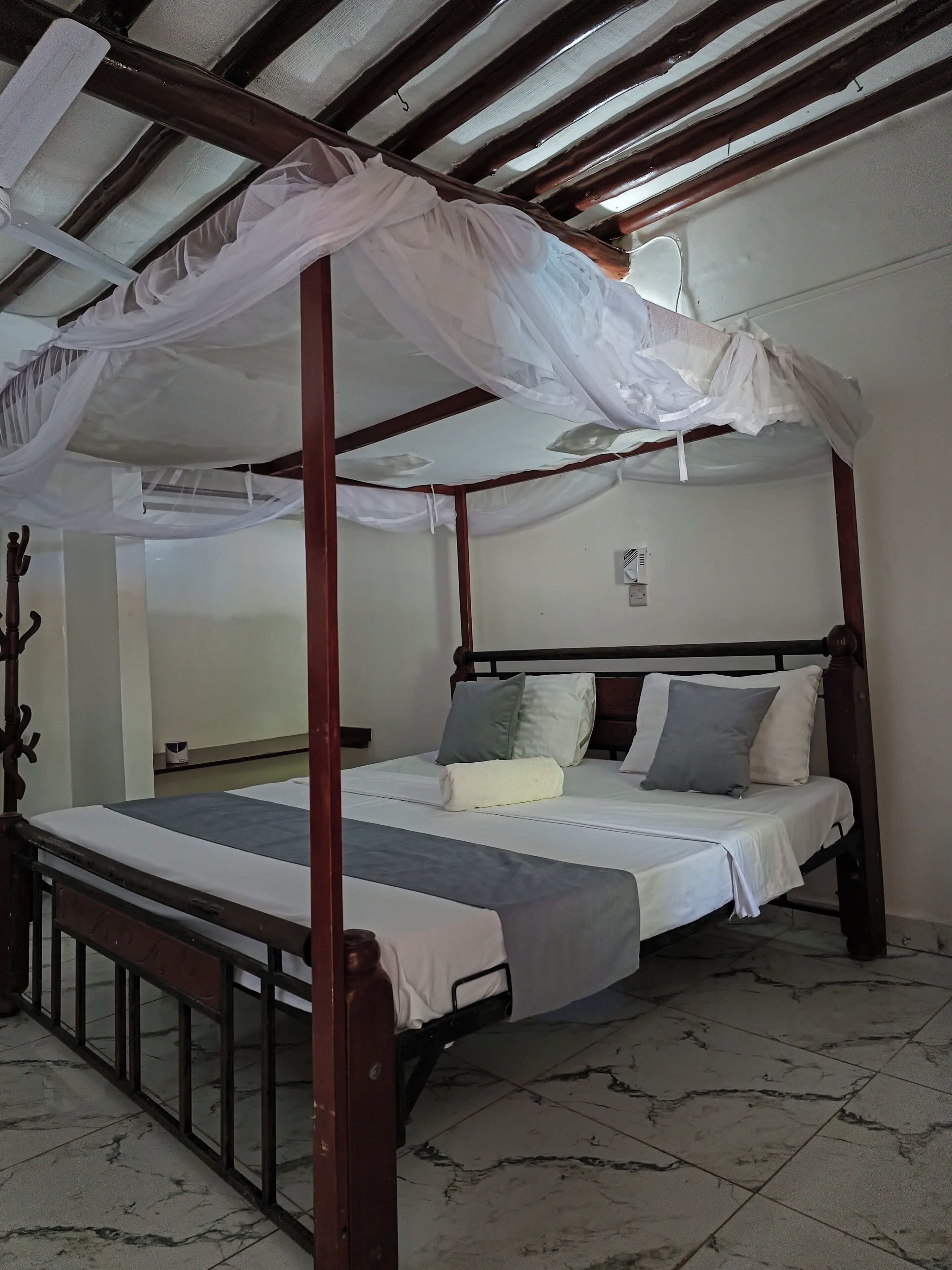 A four-poster bed with a canopy, a bedside table, and a wall-mounted air conditioning unit.